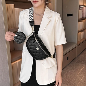 Schwarze Stepp-Gürteltasche mit gemustertem Gurt und kleinem Beutel auf weißem Blazer