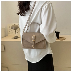 Detailed side view of khaki leather crossbody bag with crocodile pattern and gold buckle