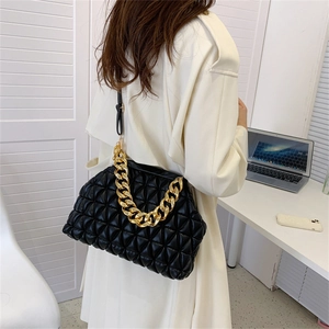 Black ruched cloud bag with gold chunky chain strap worn by model in white coat
