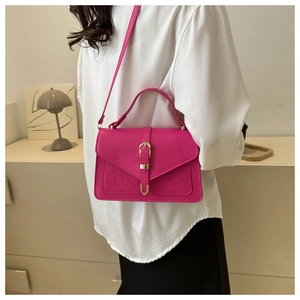 Detail view of the crocodile pattern on a fuchsia crossbody bag with golden hardware buckle