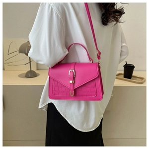 Detail of fuchsia leather bag with crocodile texture and gold U-shaped metal clasp