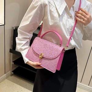 Pink glitter crossbody bag with gold ring lock shown on a model with white shirt