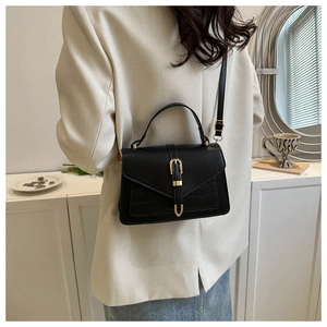 Detail showing crocodile texture and gold U-shaped buckle on black crossbody bag