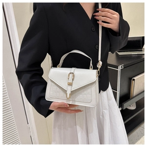 Detailed view of white crocodile pattern crossbody bag on a model wearing black and white suit