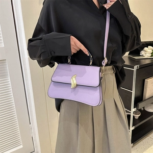 Sac à main violet élégant avec boucle dorée ondulée porté par un mannequin
