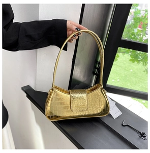 Détail du sac sous le bras doré à motif crocodile et finition métallique