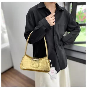 Détail du sac sous le bras doré à motif crocodile brillant avec fermeture à rabat