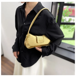 Détail du sac baguette doré à motif crocodile avec une texture métallique