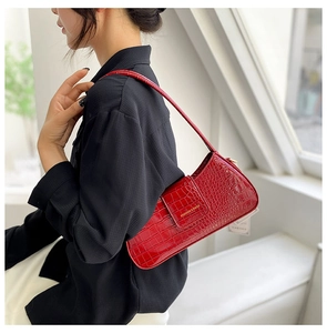 Vue détaillée du sac sous le bras rouge à motif crocodile et lettrage métallique