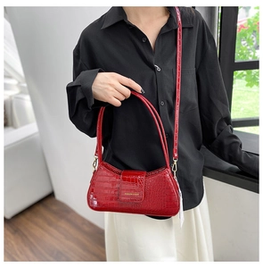 Gros plan du sac bandoulière rouge brillant en cuir verni à motif crocodile et doré