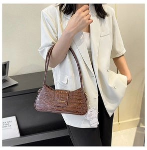 Détail du sac baguette marron foncé avec motif crocodile et logo doré élégant