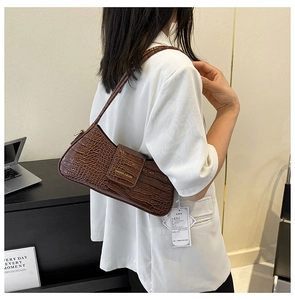 Détail de la texture crocodile marron foncé en cuir PU et boucle dorée du sac sous le bras