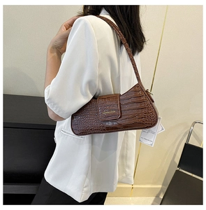 Détail du motif crocodile marron foncé gaufré sur un sac porté épaule de style baguette