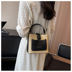 Sac seau en paille avec bordure en cuir noir et bandoulière porté par un mannequin