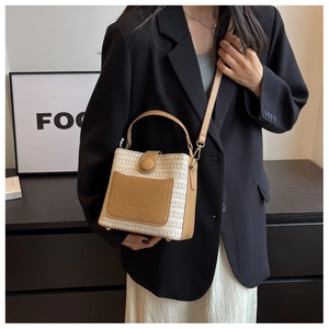 Détail du sac seau en paille tressée avec patchwork en cuir beige et fermoir magnétique
