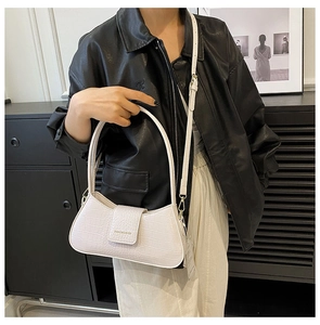 Vue détaillée d'un sac baguette blanc à motif crocodile porté en bandoulière par un mannequin