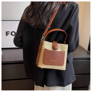 Détail du sac seau en paille tressée avec poche en cuir marron et bandoulière réglable