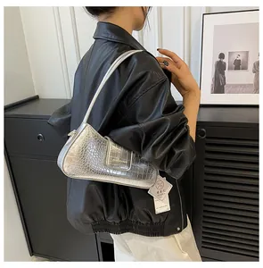 Vue latérale d'un sac hobo argenté à texture crocodile porté par un mannequin chic