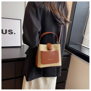 Détail d'un sac seau en paille tressée avec garniture en cuir marron et logo doré