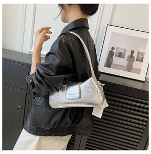 Sac baguette argenté en cuir embossé crocodile montrant la texture et le porté épaule