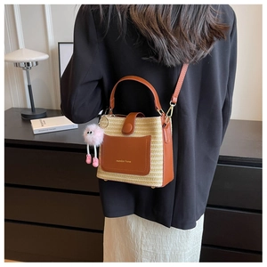 Détail du sac seau tissé avec bordure en cuir marron et breloque en peluche rose