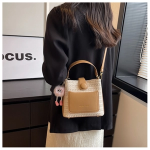 Détail du sac seau en paille tressée avec poche en cuir et breloque peluche rose au côté