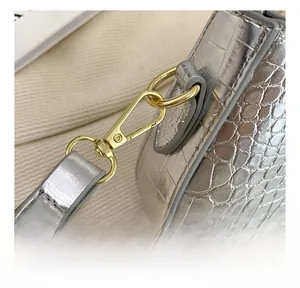 Détail du sac baguette argenté texture crocodile avec crochets en métal doré amovibles