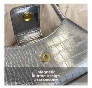 Détail du fermoir magnétique sur le sac baguette argenté avec motif crocodile