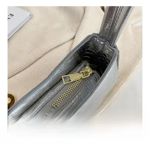 Vue détaillée de la fermeture éclair dorée sur sac à main argenté avec motif crocodile