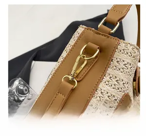 Gros plan du crochet doré sur le sac bandoulière tissé bicolore beige et marron