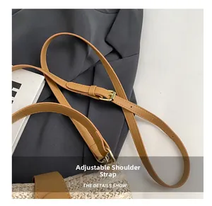Détail de la bandoulière réglable en similicuir marron avec boucle dorée sur sac paille