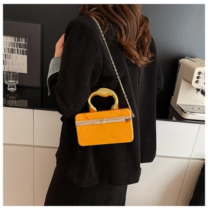 Detail of yellow acrylic marble box bag with gold metal handle and chain strap on model