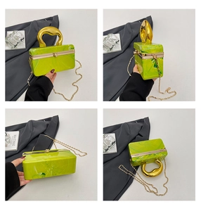 Detail of green marble acrylic evening bag with gold liquid-textured handle and chain
