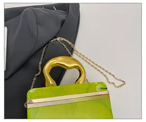 Macro shot of green marble acrylic clutch featuring unique gold-tone metal handle and chain