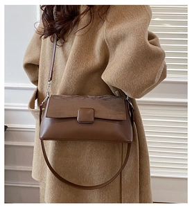 Detail einer braunen Vintage-Schultertasche mit mattem Quadratverschluss und Texturoptik