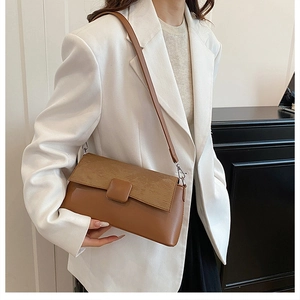 Nahaufnahme der braunen Vintage-Unterarmtasche mit Texturmix und eckiger Schnalle am Model