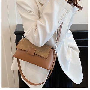 Detailansicht einer braun-beigen Schultertasche kombiniert mit einem weißen Blazer