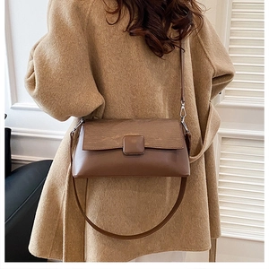 Nahaufnahme der braunen Vintage-Leder-Umhängetasche an einem Modell mit Wollmantel