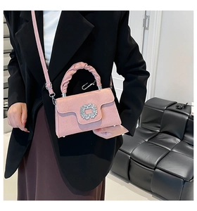 Detail of pink pleated handbag featuring a crystal square buckle and crossbody strap