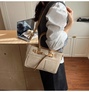 Beige fabric tote bag with brown leather trim shown on model in cozy office setting