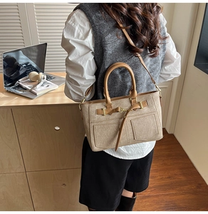 Detail of khaki canvas and leather patchwork tote bag featuring dual pockets and buckles
