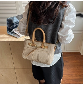 Dettaglio della borsa tote in tela beige con manici in pelle marrone e cinturino laterale