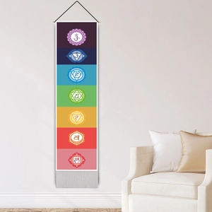 Vertikaler Wandteppich mit sieben Chakren, Symbolen und Quasten an weißer Wand