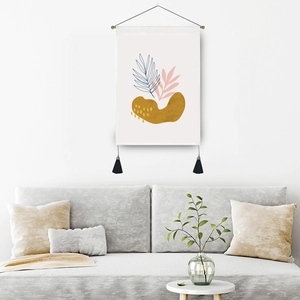 Modern abstract wall tapestry with botanical prints and black tassels in a minimalist room