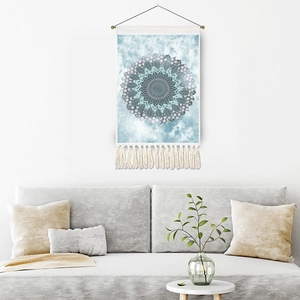 Blue tie-dye mandala tapestry with tassels hanging over a modern grey sofa
