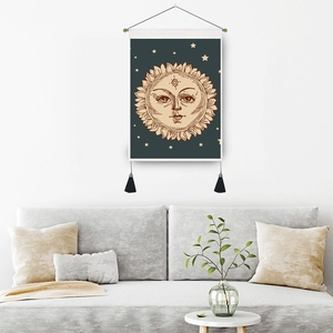 Bohemian sun deity tapestry with black tassels hanging over a sofa in a living room