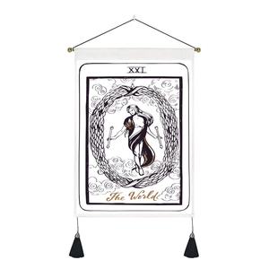 Detail of The World tarot tapestry with white fabric, black illustrations, and gold tassels