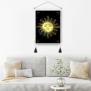 Bohemian black tapestry with golden sun totem and tassels hanging on a white wall