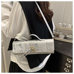 Détail d'un sac argenté à motif crocodile avec éclat métallique et fermoir doré en nœud