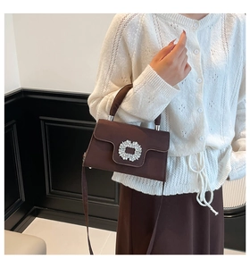 Close-up of dark brown square bag with pleated leather and luxury rhinestone flower buckle